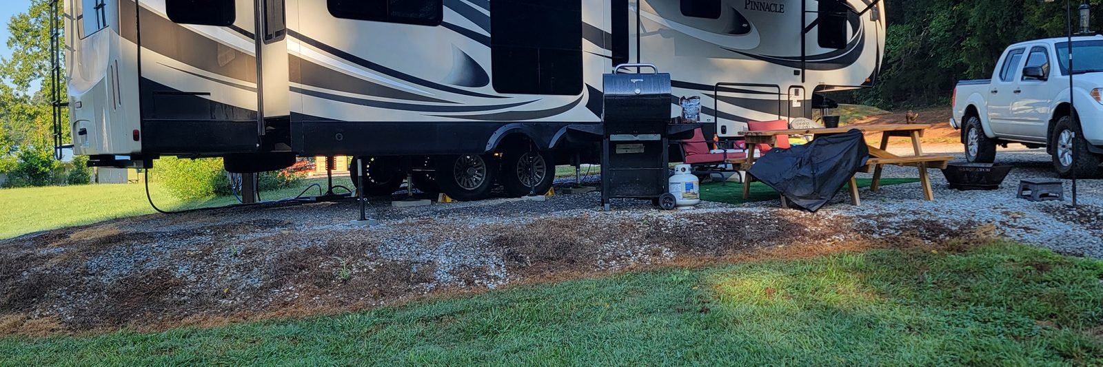A fifth wheel set up on its site at Gryptid RV Park with a pickup parked alongside