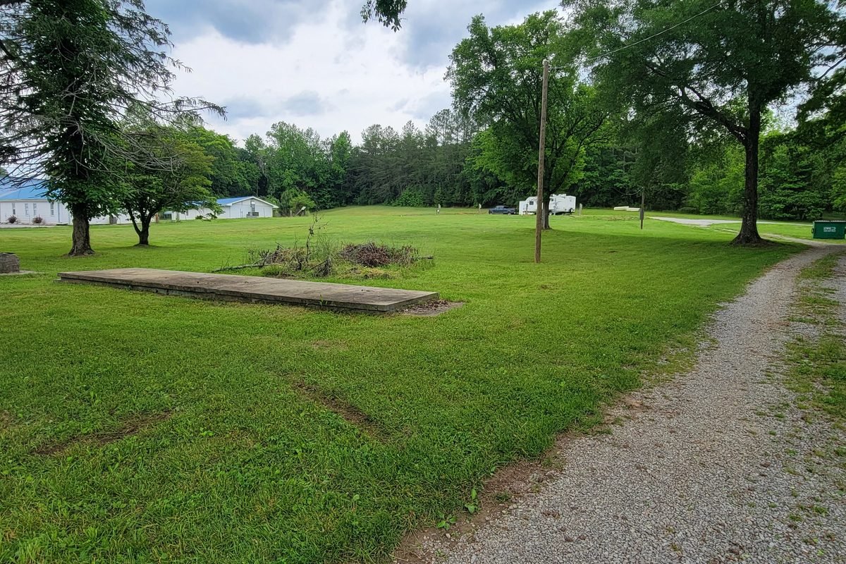 Old concrete slabs sitting in the grass from the previous layout, gravel drive alongside