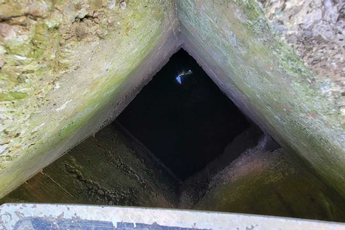 Looking down inside the old well shaft, water visible at the bottom