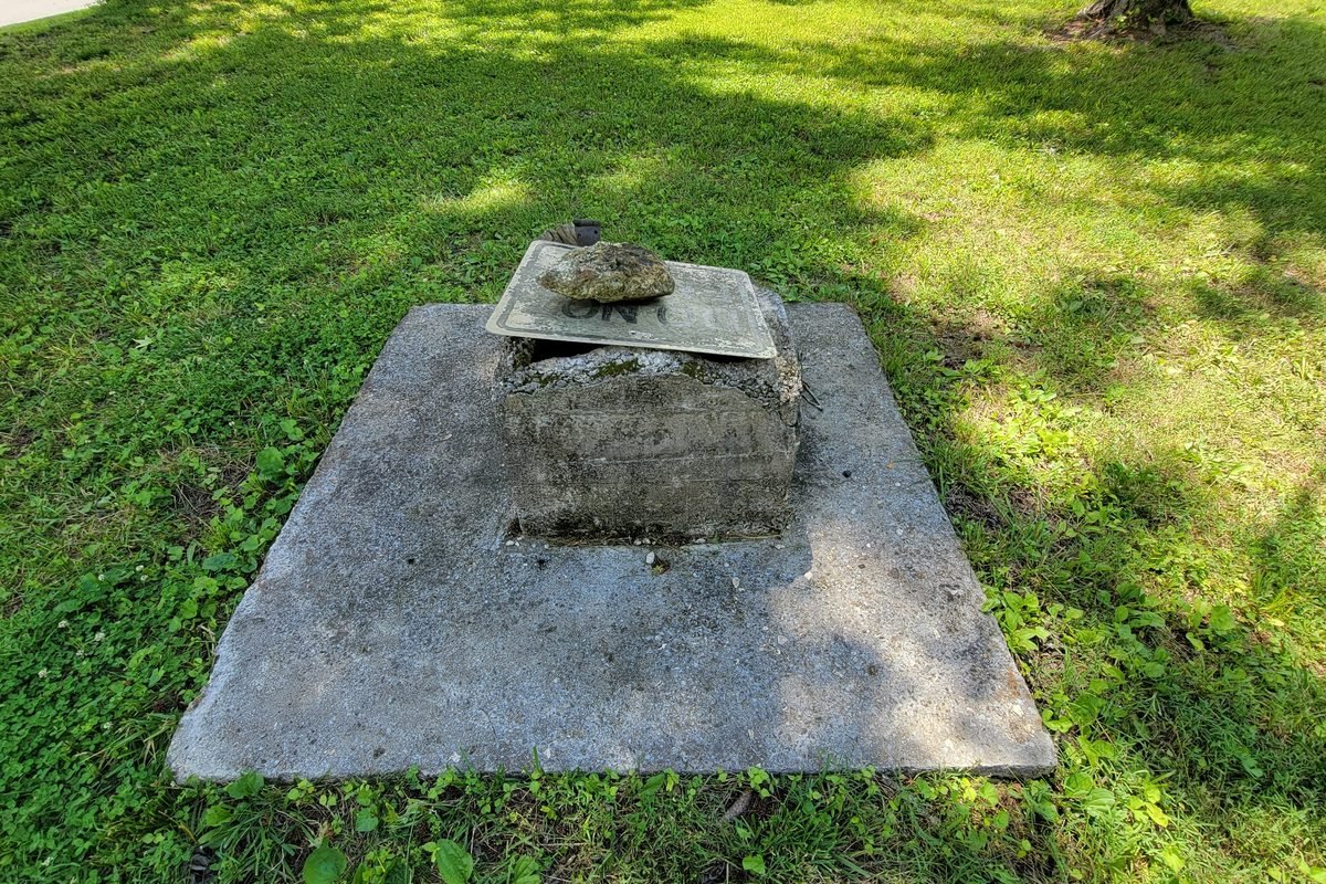 A concrete cap over an old hand dug well set into the grass
