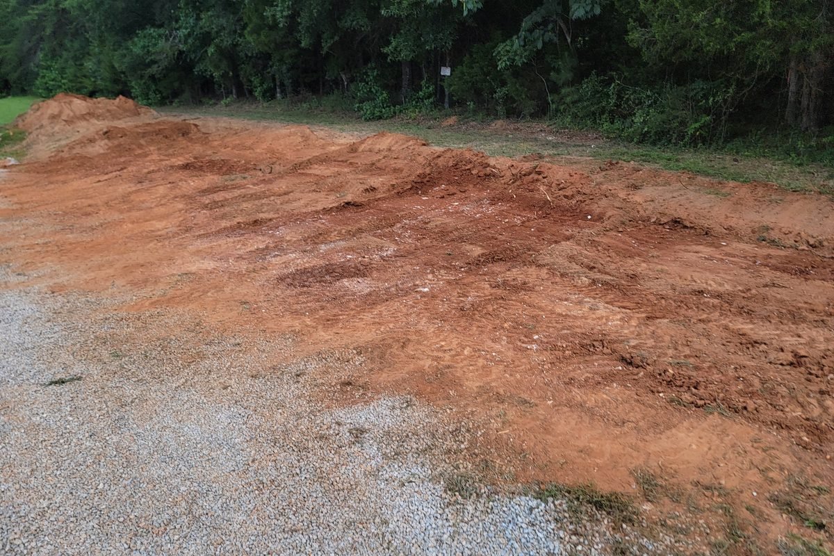 A level pad graded out of red clay with gravel drive alongside