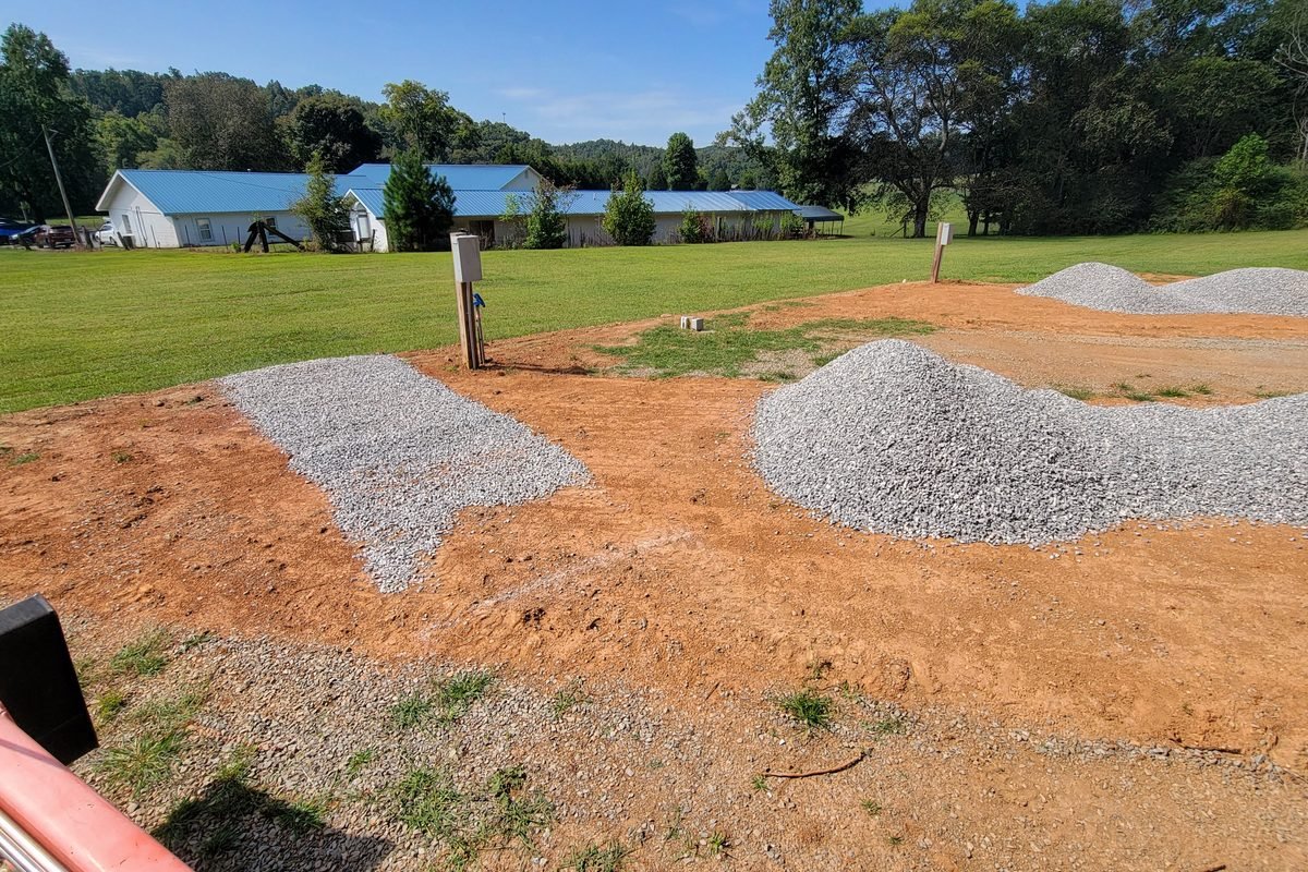 Piles of grey gravel dropped across the graded pads waiting to be spread