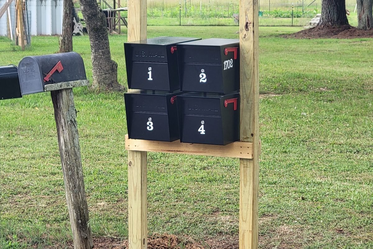Four mailboxes numbered one to four on a timber frame at the road