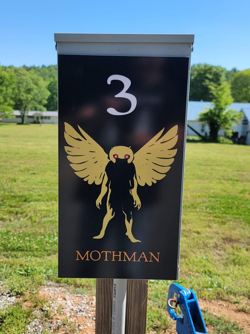 Site 3 pedestal panel, a gold winged Mothman figure on black