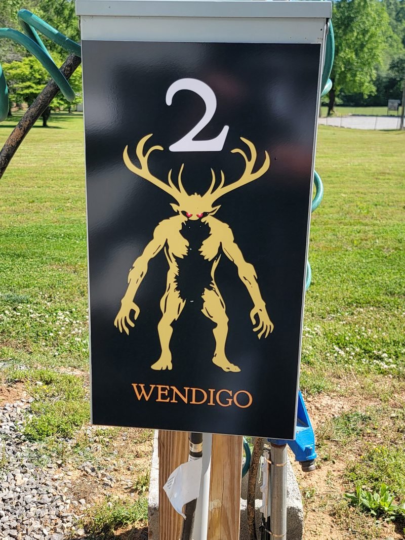 Site 2 pedestal panel, a gold antlered Wendigo figure on black